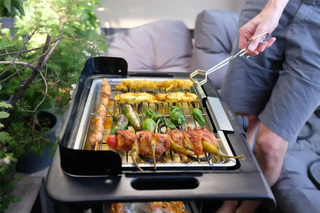 Leckeres Grillen auf dem Balkon: Spieße mit Fleisch und Gemüse brutzeln auf dem Elektrogrill.