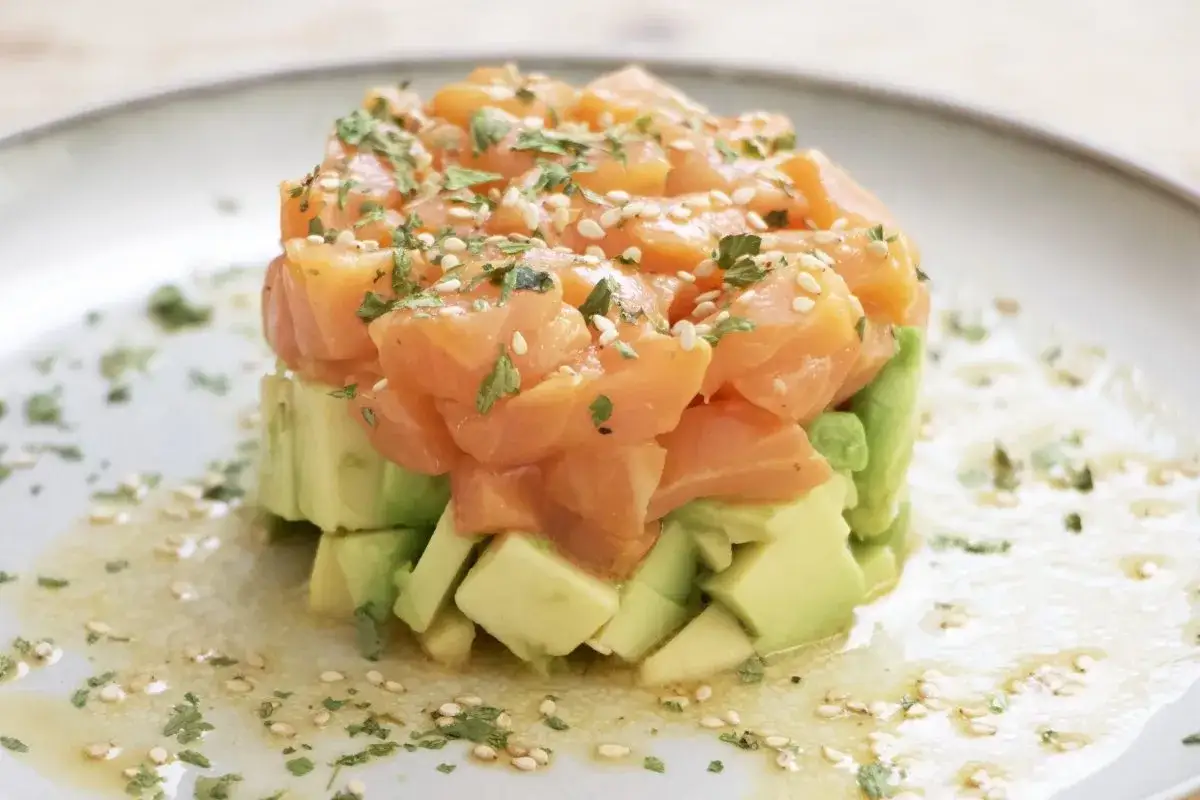Delicioso tartar de salm&oacute;n ahumado y aguacate, ideal para tus recetas con salm&oacute;n ahumado. Adornado con s&eacute;samo y perejil.