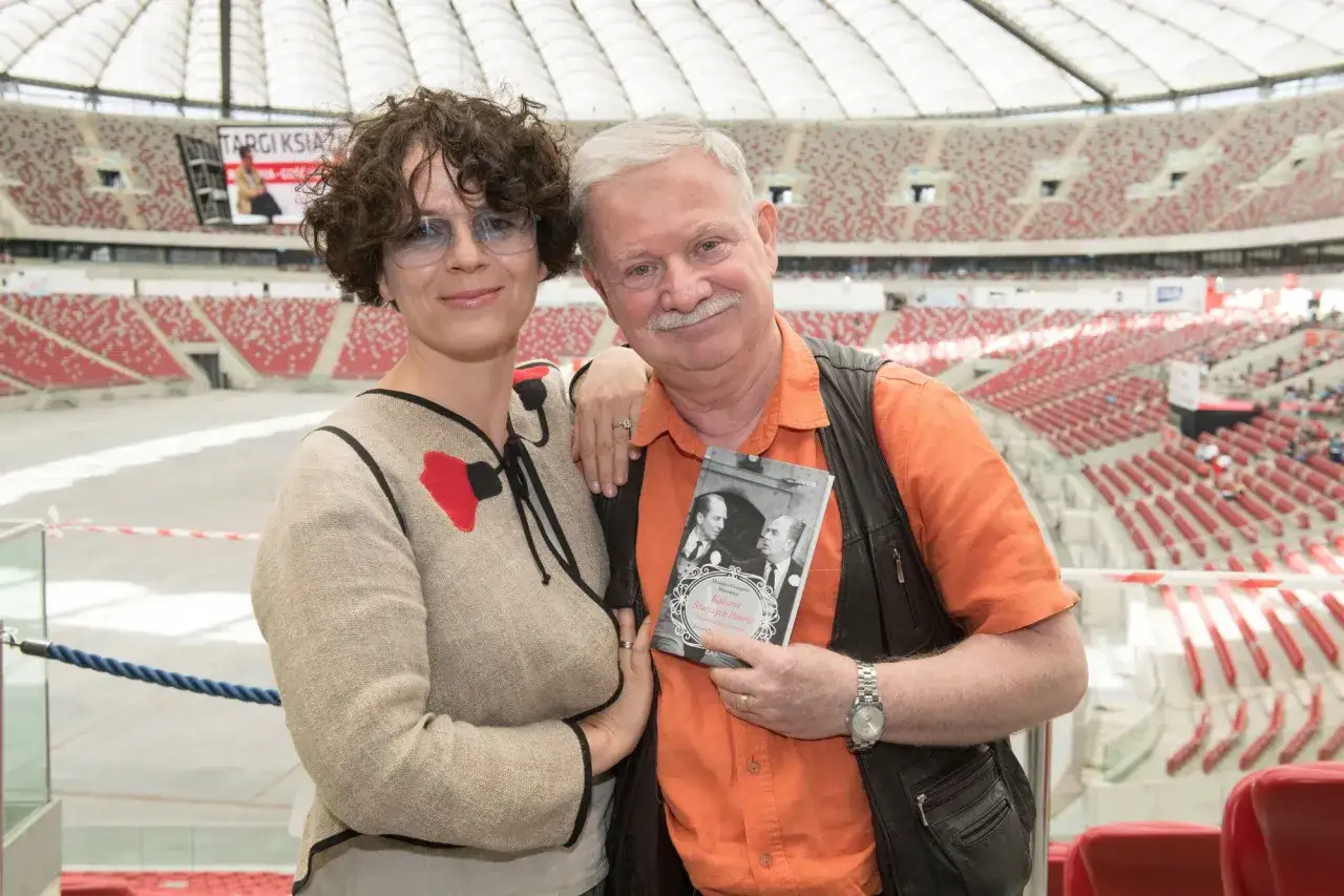 Grzegorz Wasowski i Monika Olejnik na tle stadionu, prezentują książkę.