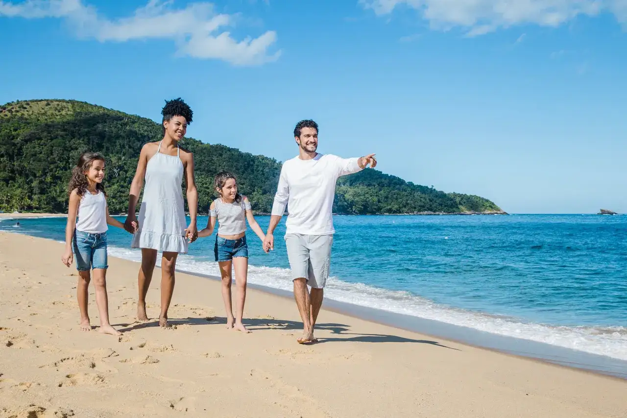 Familia paseando por la playa, disfrutando de un día soleado. ¡Unas vacaciones perfectas de ibiza con niños!