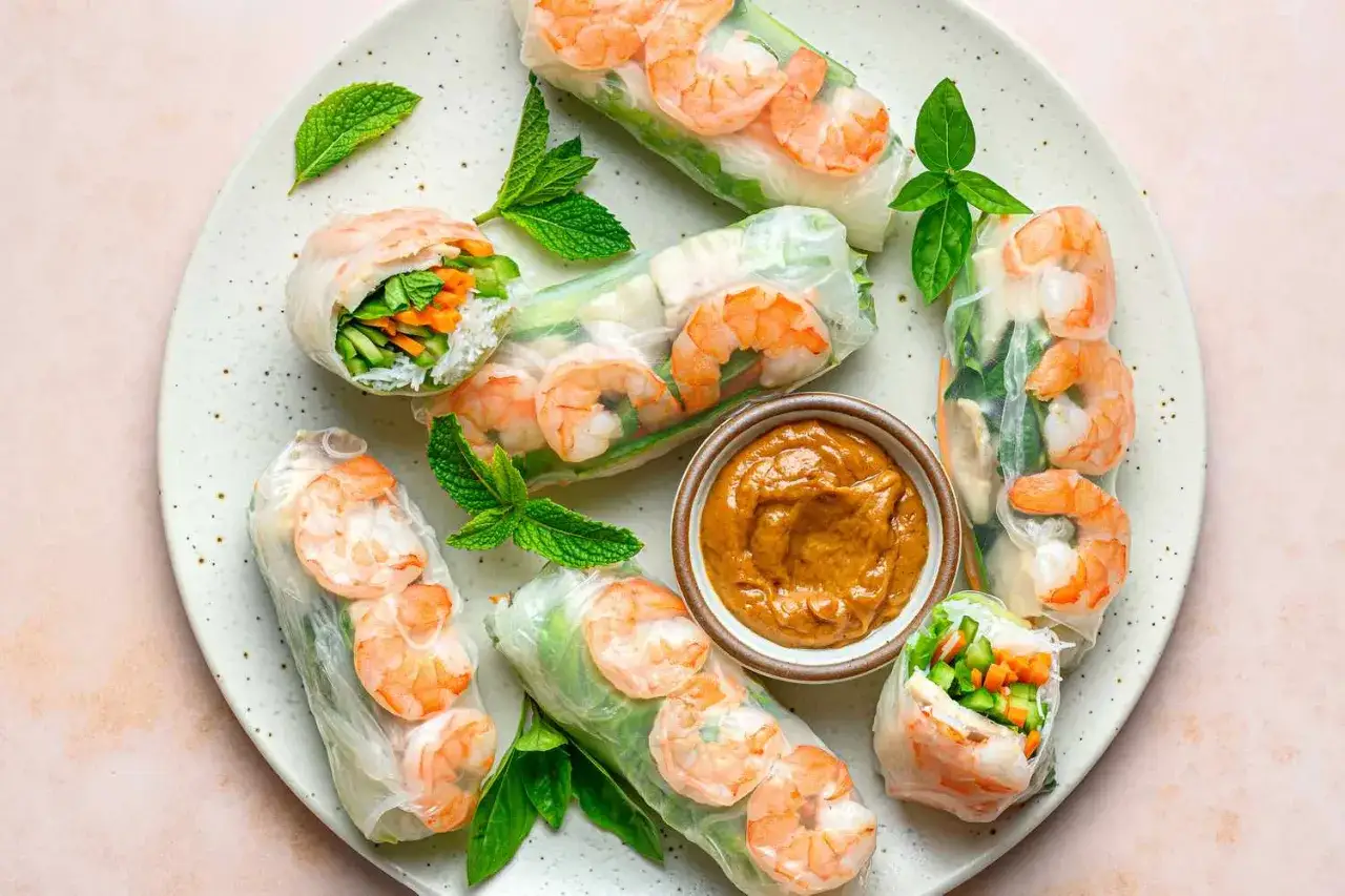 Frische Sommerrollen mit Garnelen, Gemüse und Minze, serviert mit Erdnusssauce. Perfekt für ein leichtes Sommerrollen Rezept.