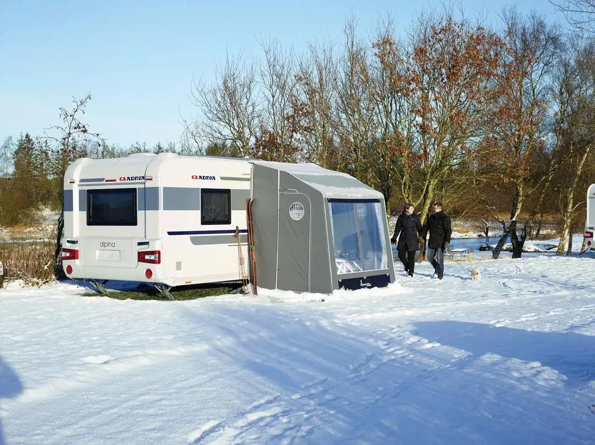 Vintercamping i Haparanda med en Adria Alpina husvagn. Ett par promenerar i sn&ouml;n med sin hund. En perfekt plats f&ouml;r din best caravan Haparanda.