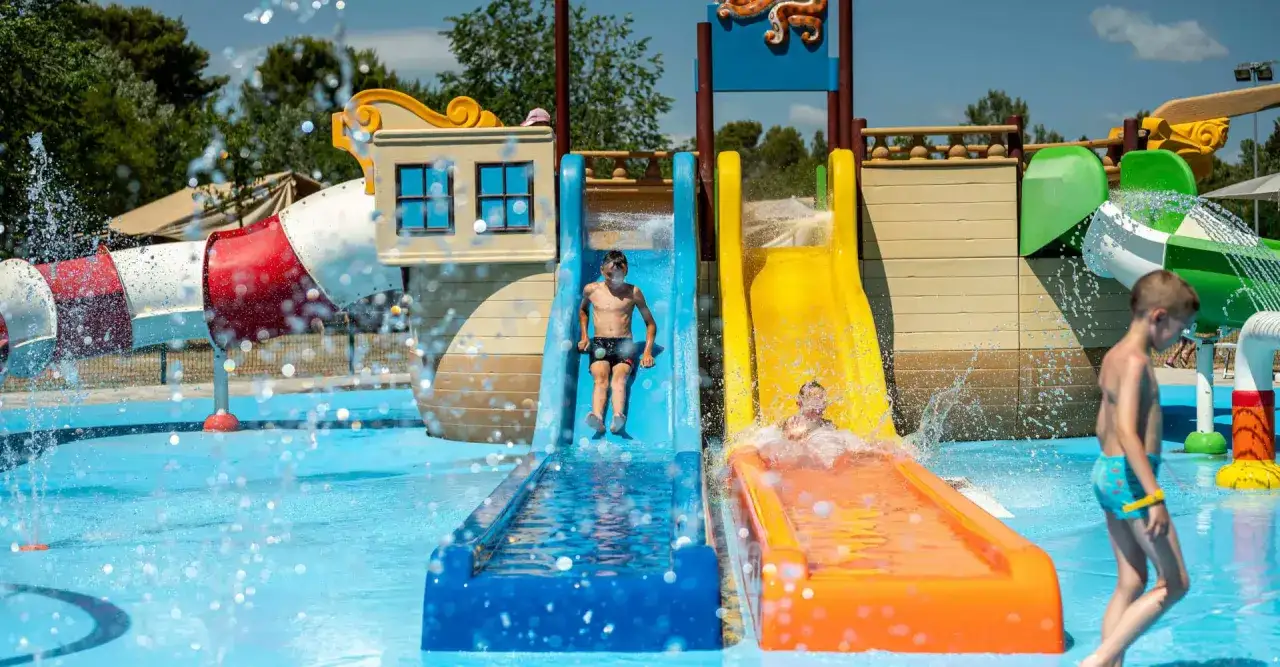Dzieci szaleją na zjeżdżalniach wodnych w bi village camping. Radość i plusk wody w letni dzień.