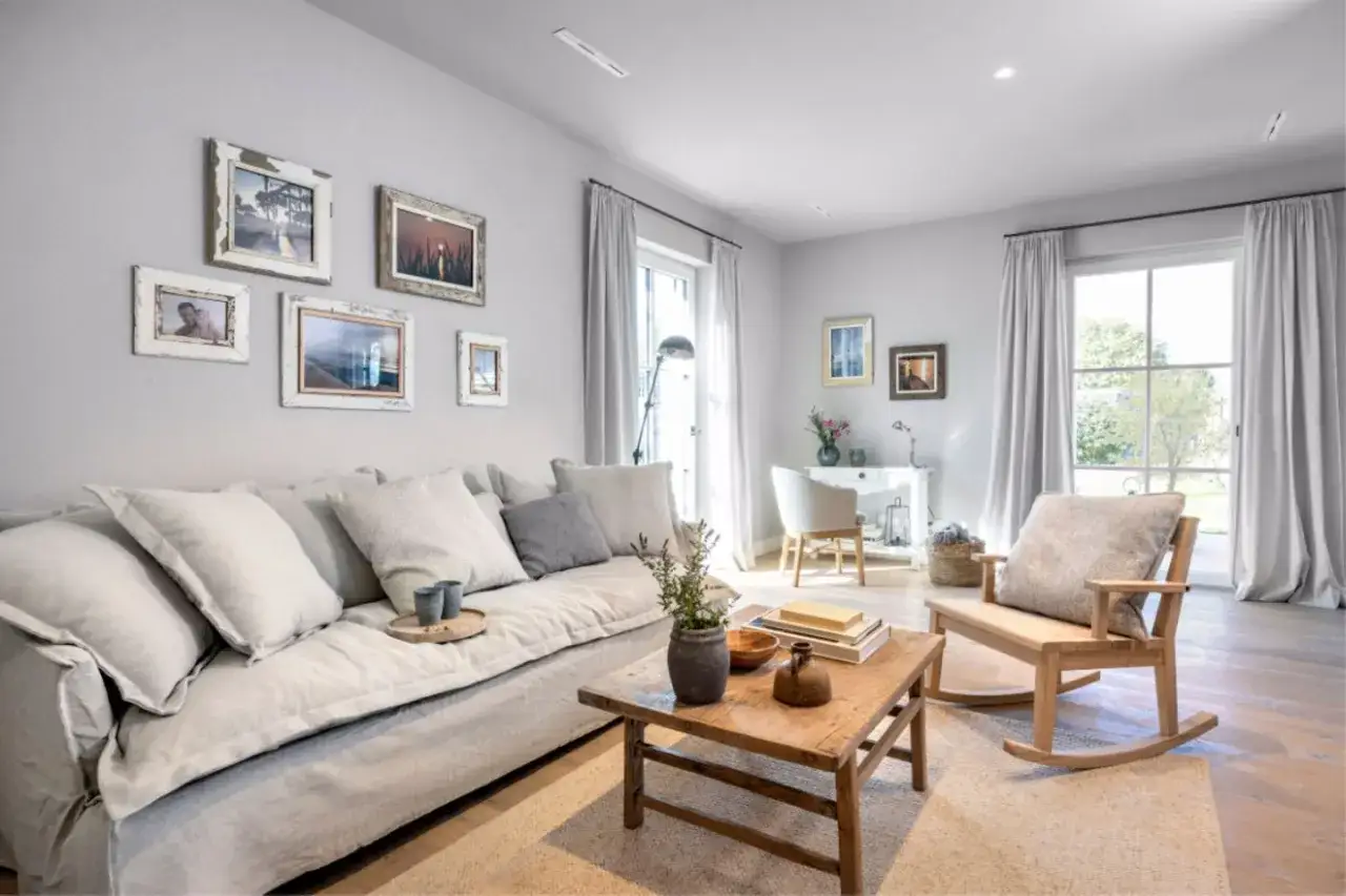 Gemütliches Wohnzimmer in millennial grey mit großem Sofa, Holztisch und Schaukelstuhl.