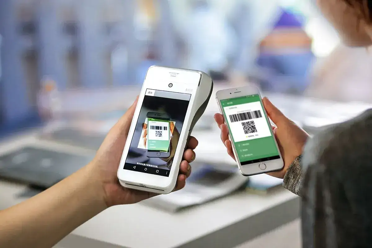 Pago móvil con códigos QR. Una persona usa su móvil para pagar en un terminal, mostrando la app de Bankinter Empresas.