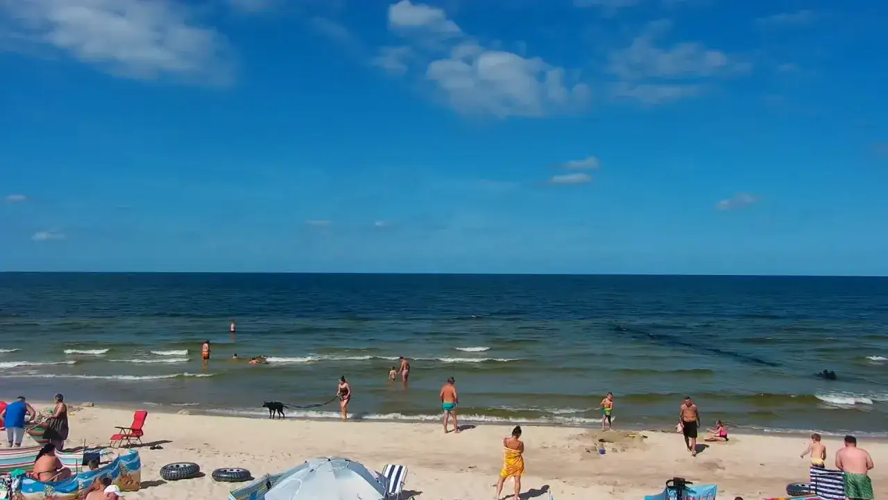 Słoneczna plaża w Mrzeżynie, ludzie kąpią się i spacerują. To idealne miejsce na wakacyjne atrakcje.
