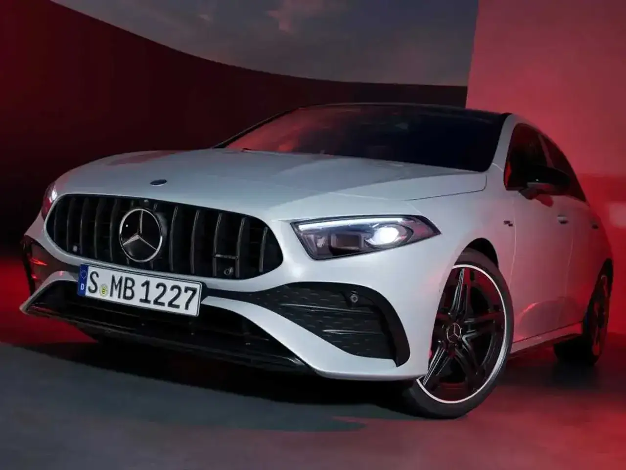 Sportlicher Mercedes A-Klasse mit markantem K&uuml;hlergrill und AMG-Felgen, beleuchtet von rotem Licht.
