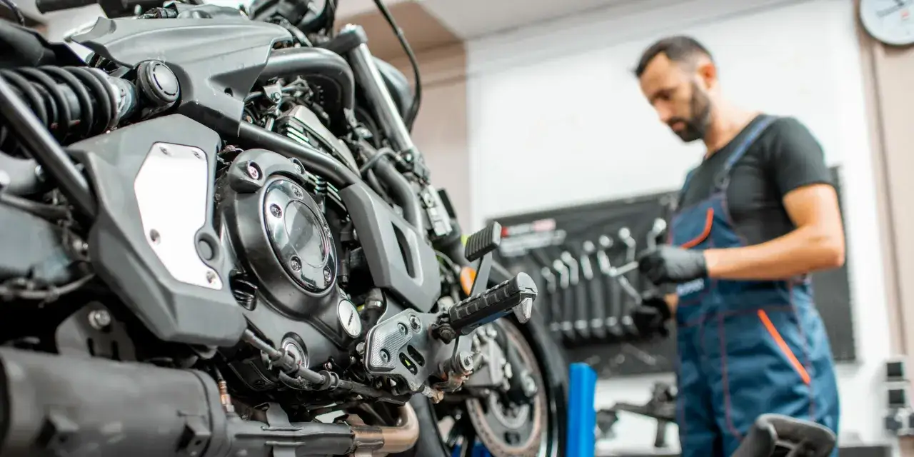 Mec&aacute;nico revisa moto. Conoce el **precio cambio aceite moto** y otros servicios.