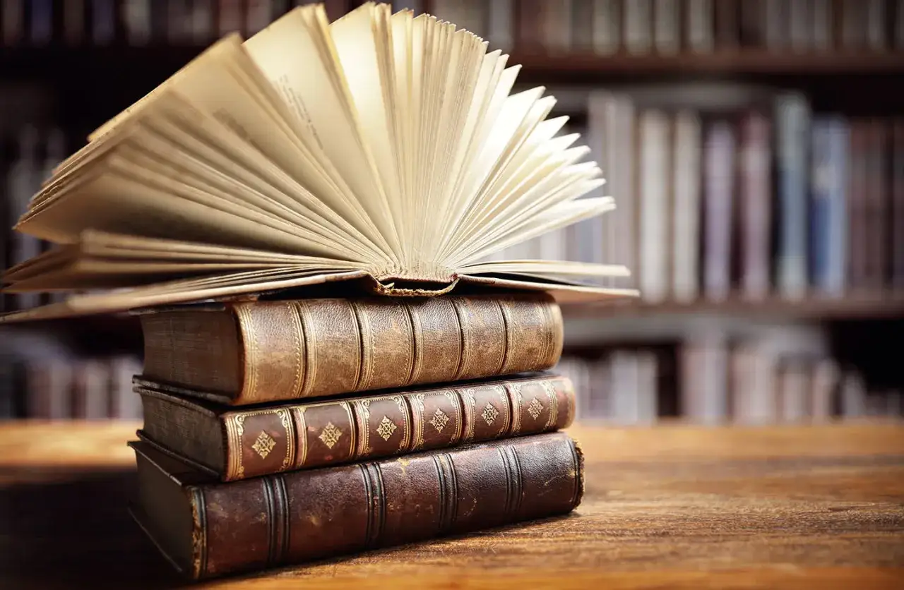 Stos starych ksiąg, otwarty tom na górze. Idealny obraz dla osób zainteresowanych bibliotekoznawstwo studia.