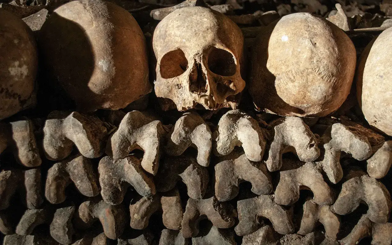 En närbild av mänskliga skallar och ben som staplats i Paris katakomber. En kuslig påminnelse om historien.