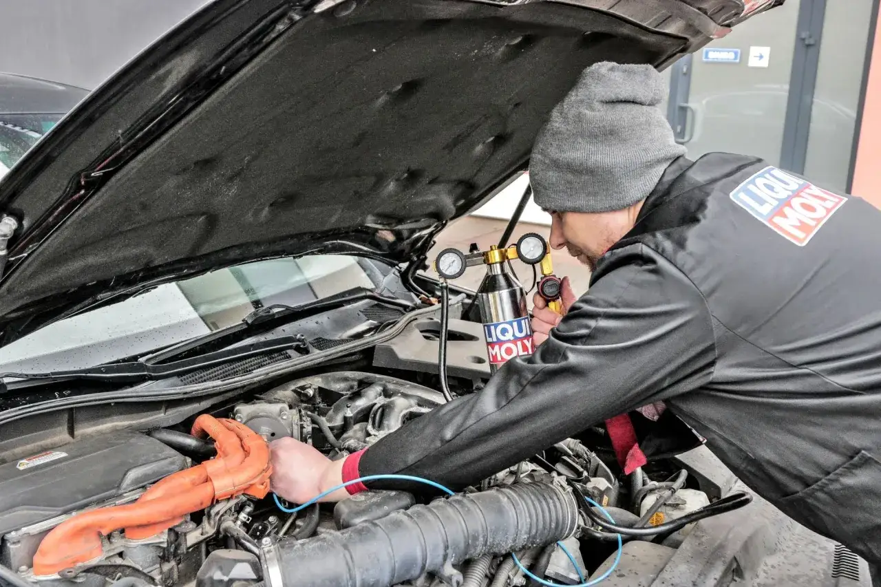 Mechanik z urządzeniem do czyszczenia katalizatora w samochodzie.