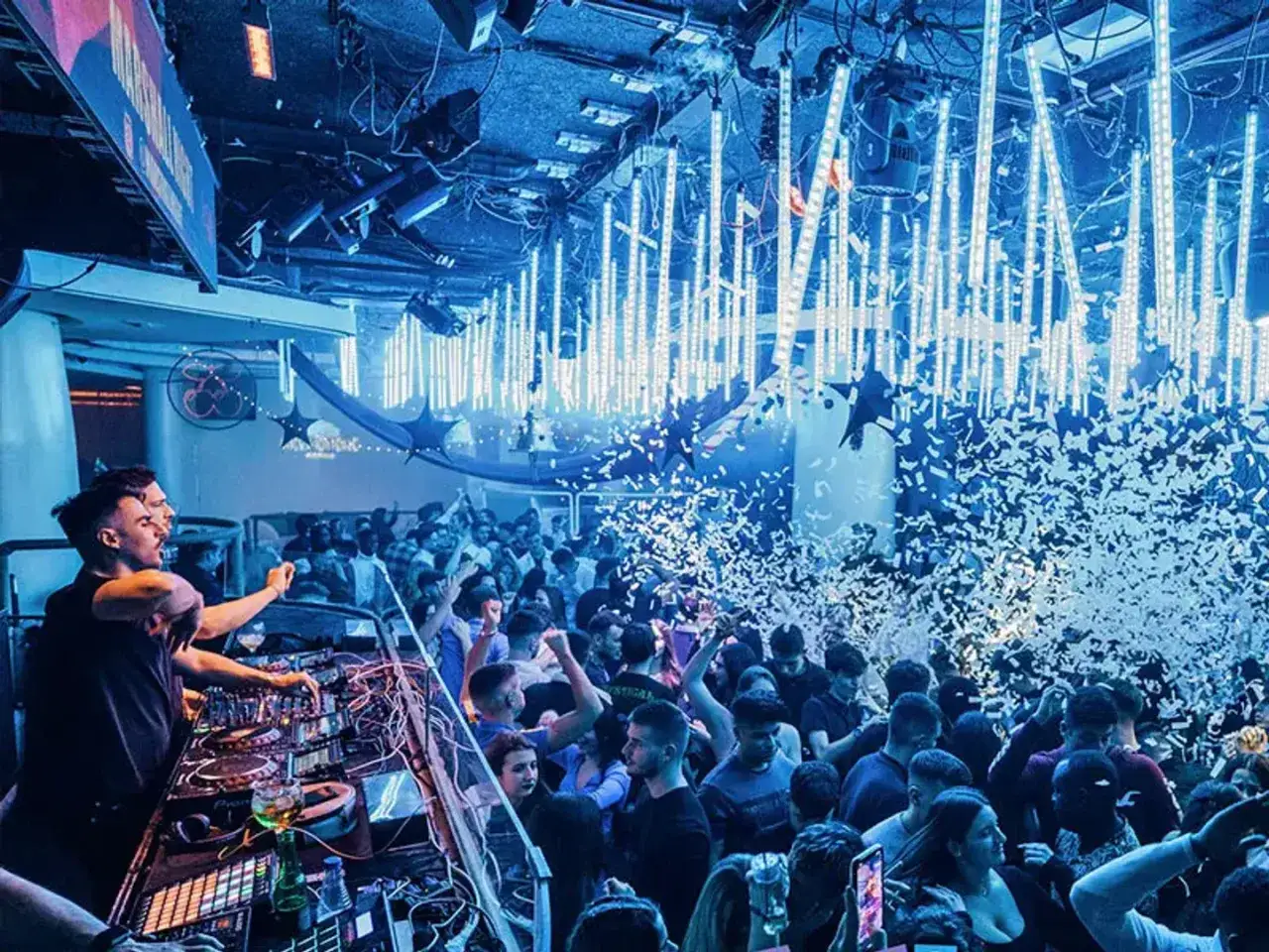 Festa scatenata al Felina Club Barcellona con coriandoli e luci blu. DJ set coinvolgente per una folla in delirio.