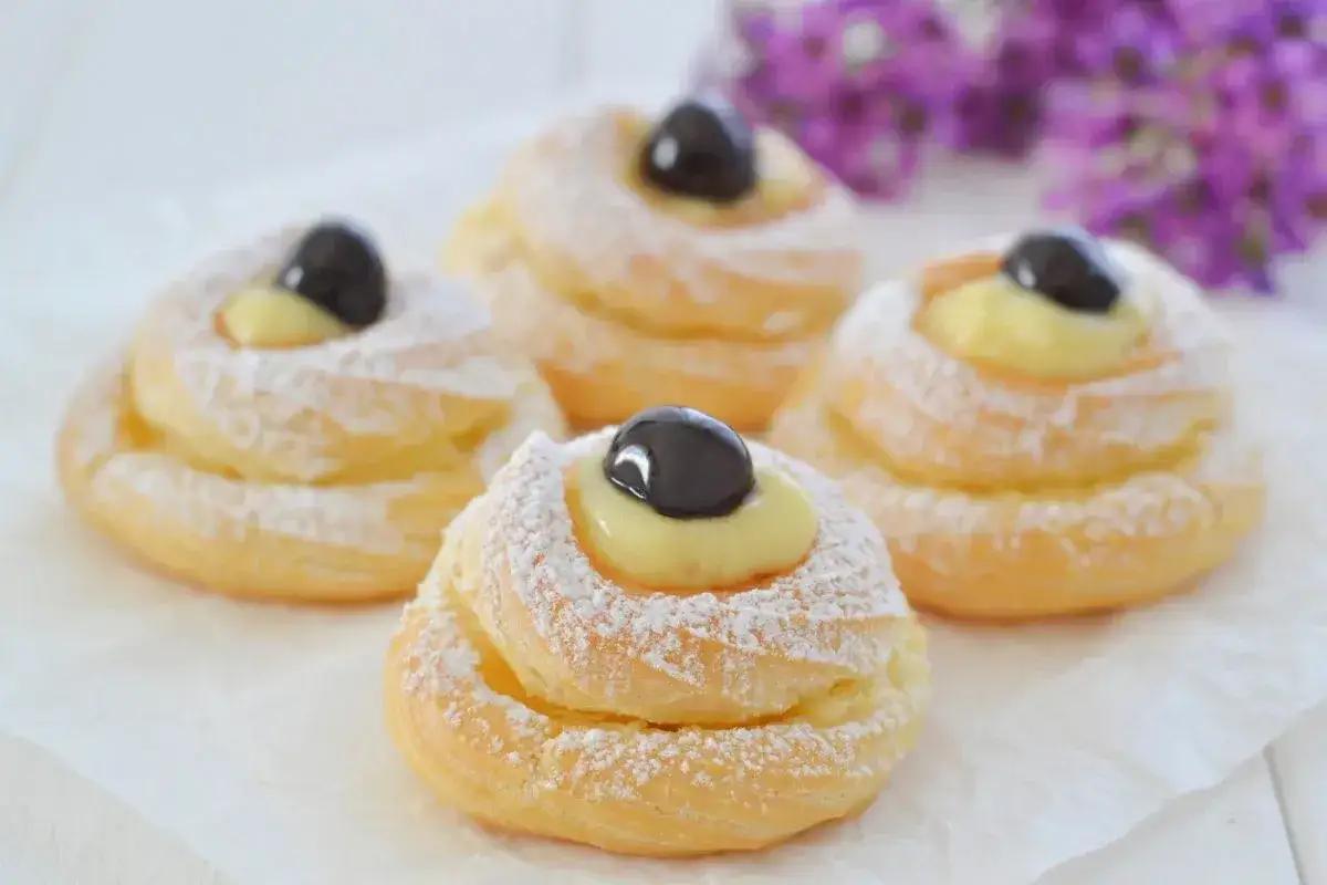 Zeppole di San Giuseppe: un dolce che racconta una storia di tradizione e gusto, con crema pasticcera e ciliegia candita.