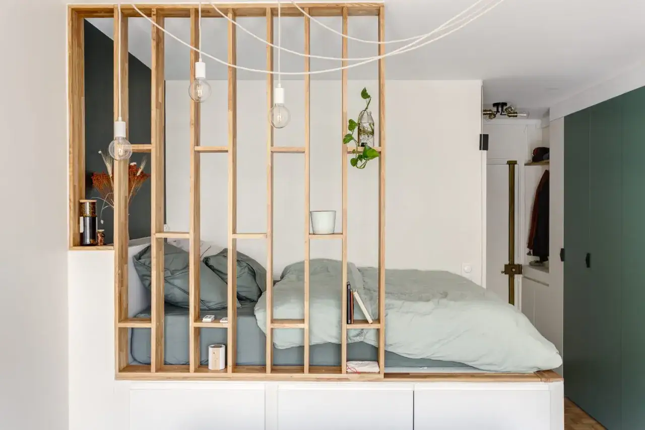 Aménagement ingénieux d'un studio T2 avec un lit douillet séparé par une étagère en bois.