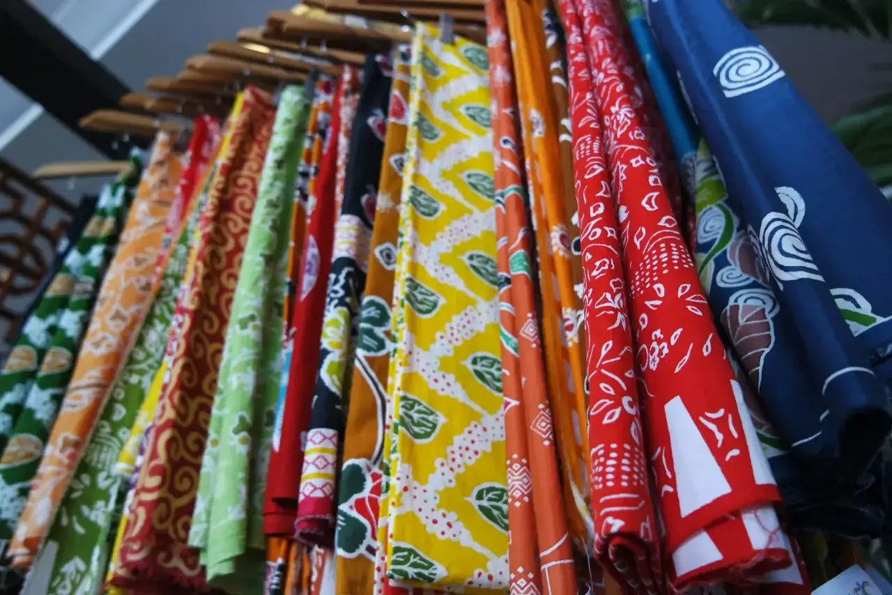 Une rang&eacute;e de tissus color&eacute;s aux motifs vari&eacute;s, comme un arc-en-ciel de batik. Chaque pi&egrave;ce arbore un motif all over unique, des spirales aux feuilles, dans des teintes vives.