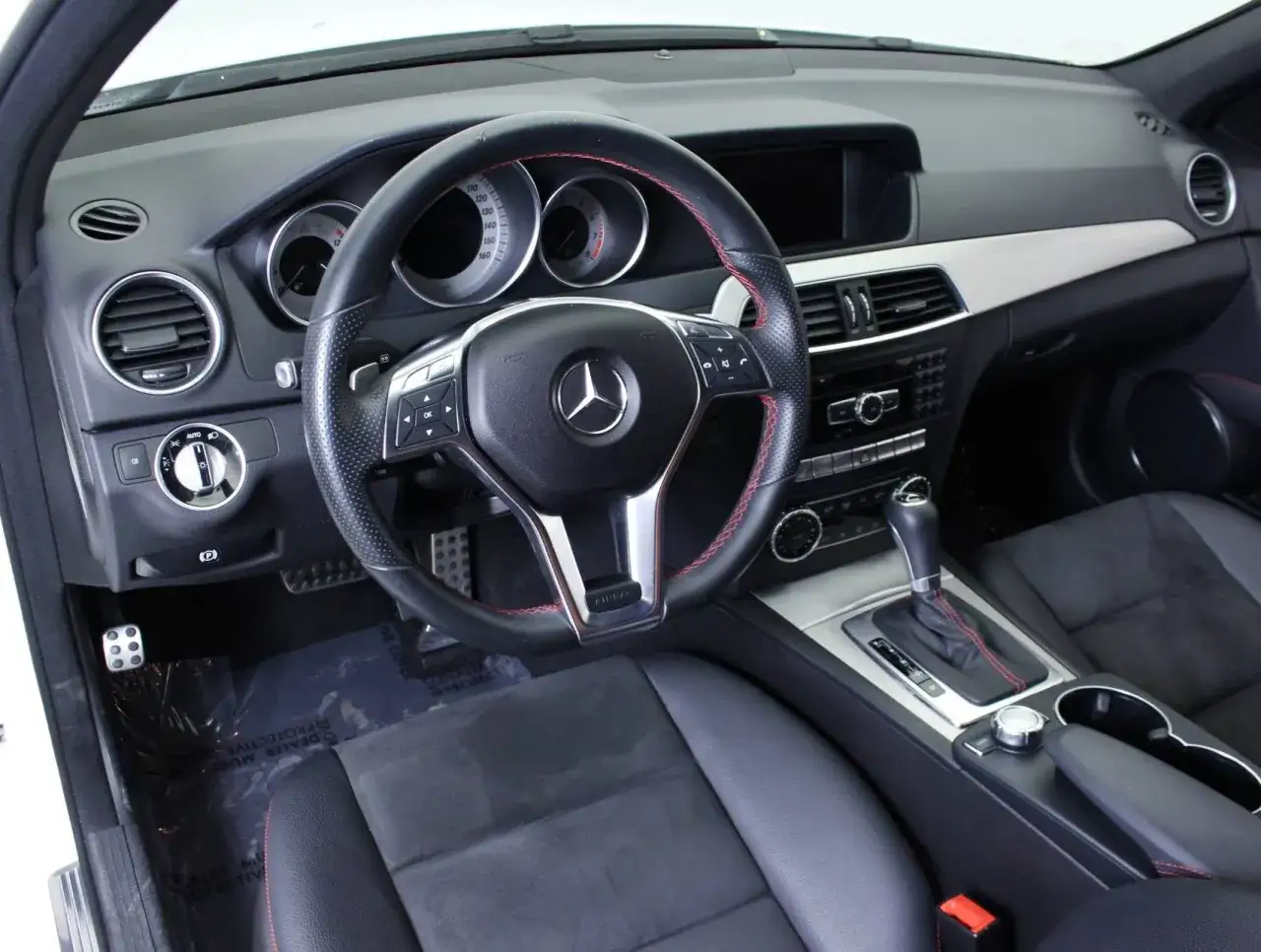 Interi&ouml;r i en Mercedes C-klass med sportratt och r&ouml;da s&ouml;mmar. Kanske ett problem med instrumentpanelen?