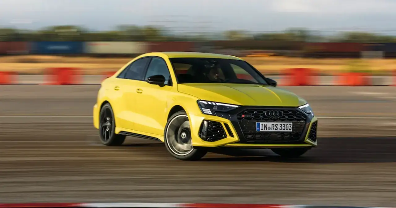 Ż&oacute;łte Audi RS3 na torze, gotowe do bicia rekordu 0-100 km/h. Dynamiczna jazda i sportowy wygląd.