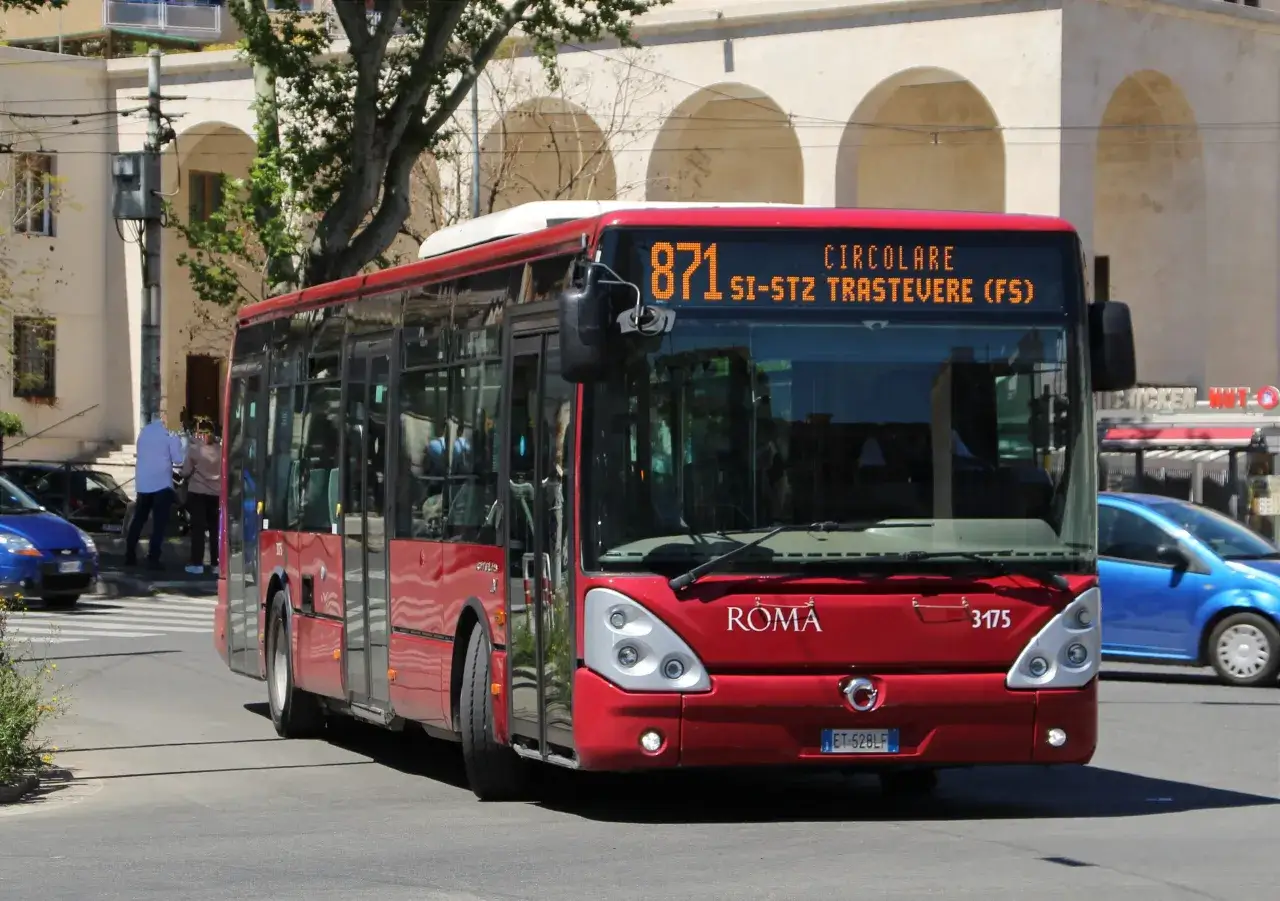 Autobus rosso della linea 871, destinazione Trastevere, attraversa una strada di Roma.