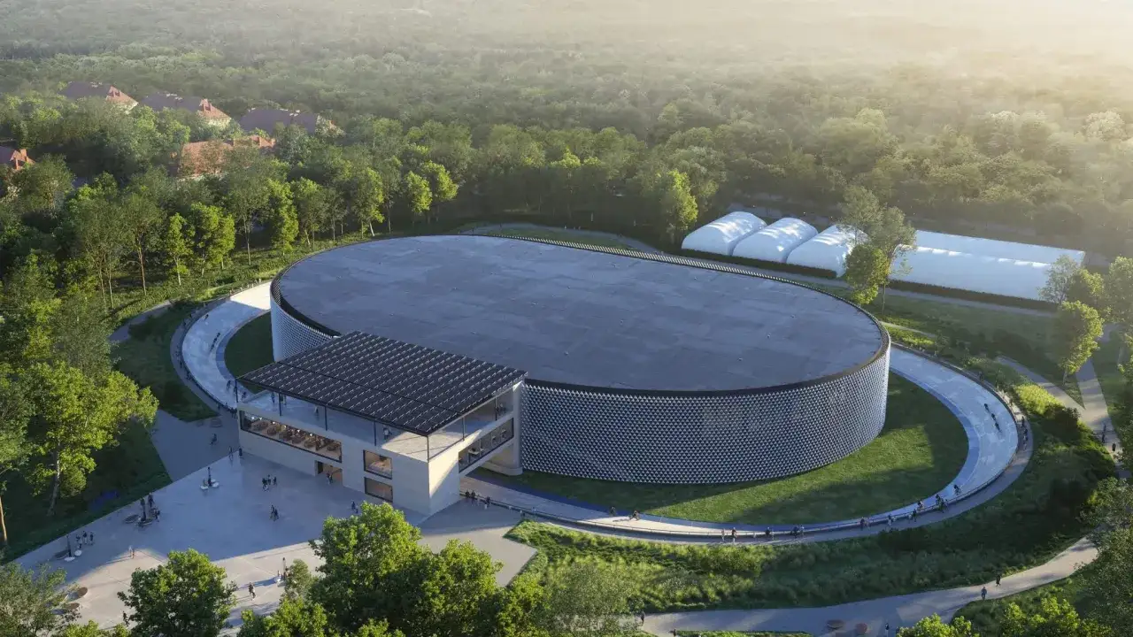 Nowoczesny welodrom co to? Owalu budynek z panelami słonecznymi, otoczony zielenią i ścieżkami, gdzie trenują kolarze.