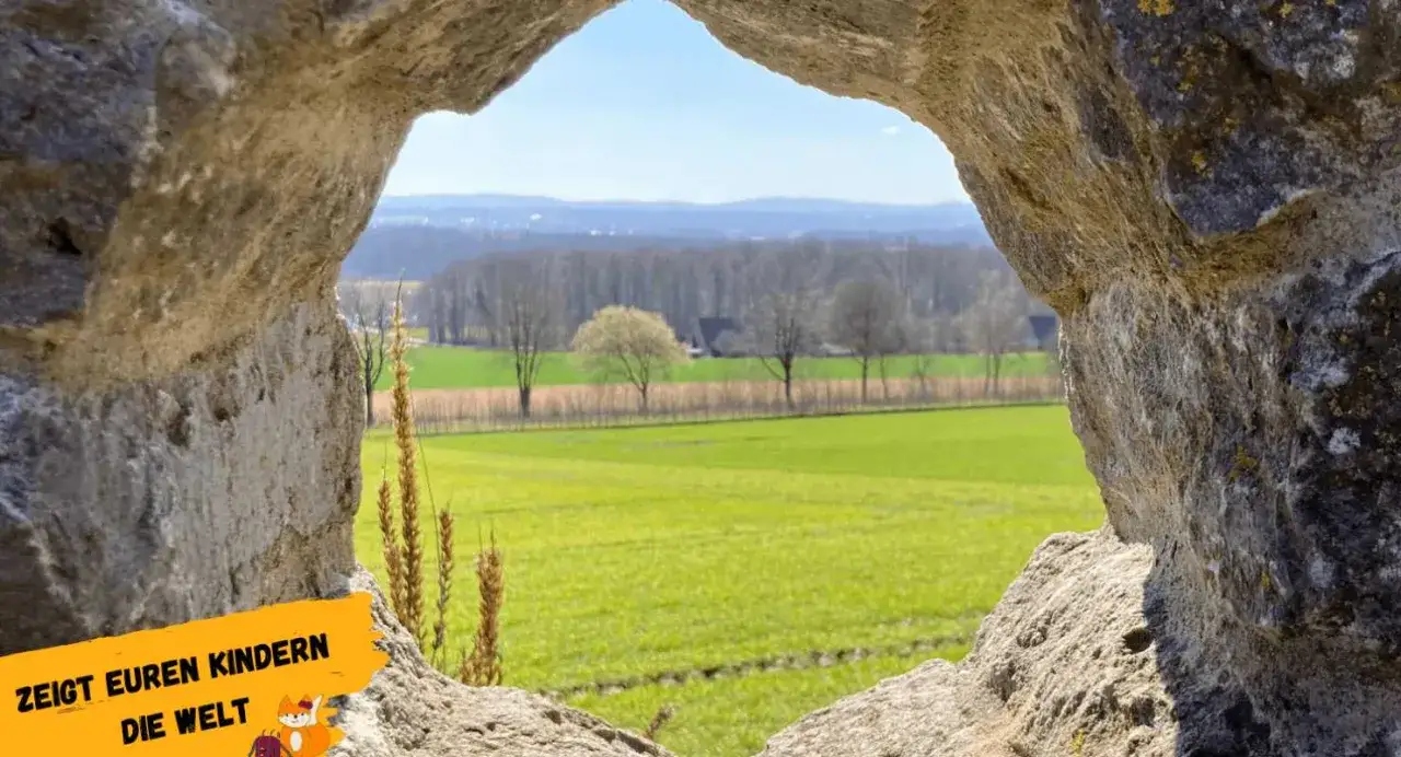 Blick durch einen Felsdurchbruch auf grüne Felder und Bäume. Perfekt für Ausflugsziele OWL mit Kindern, um die Welt zu entdecken.