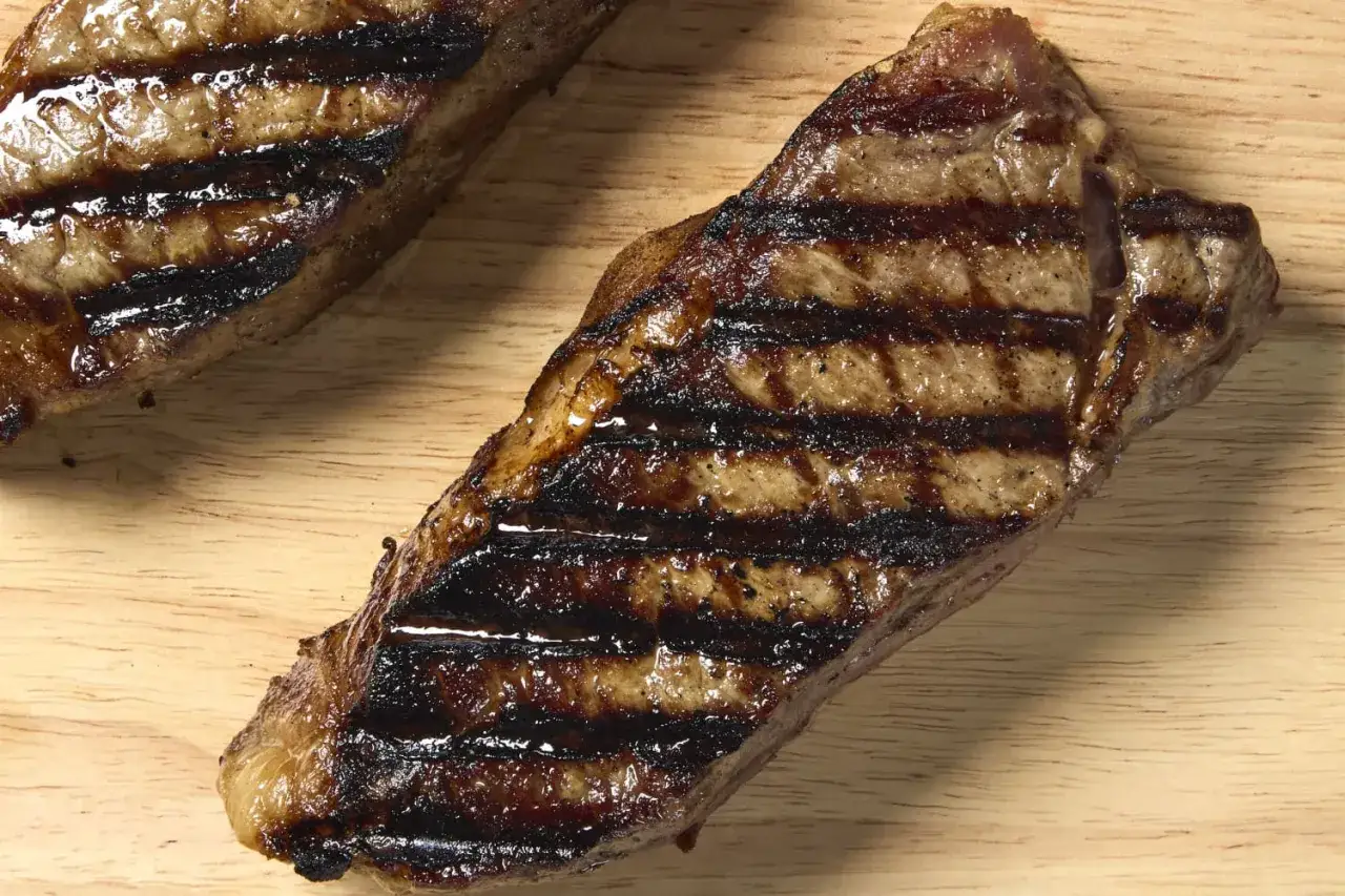 Deux entrec&ocirc;tes grill&eacute;es, savoureuses et juteuses, pos&eacute;es sur une planche en bois. Parfaites pour un repas gourmand.