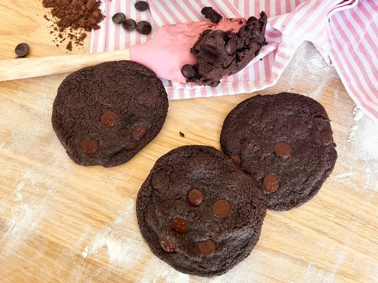 Schokoladige Kekse, perfekt für ein Subway Cookies Rezept. Mit Schokostückchen und Kakaopulver auf Holzbrett.