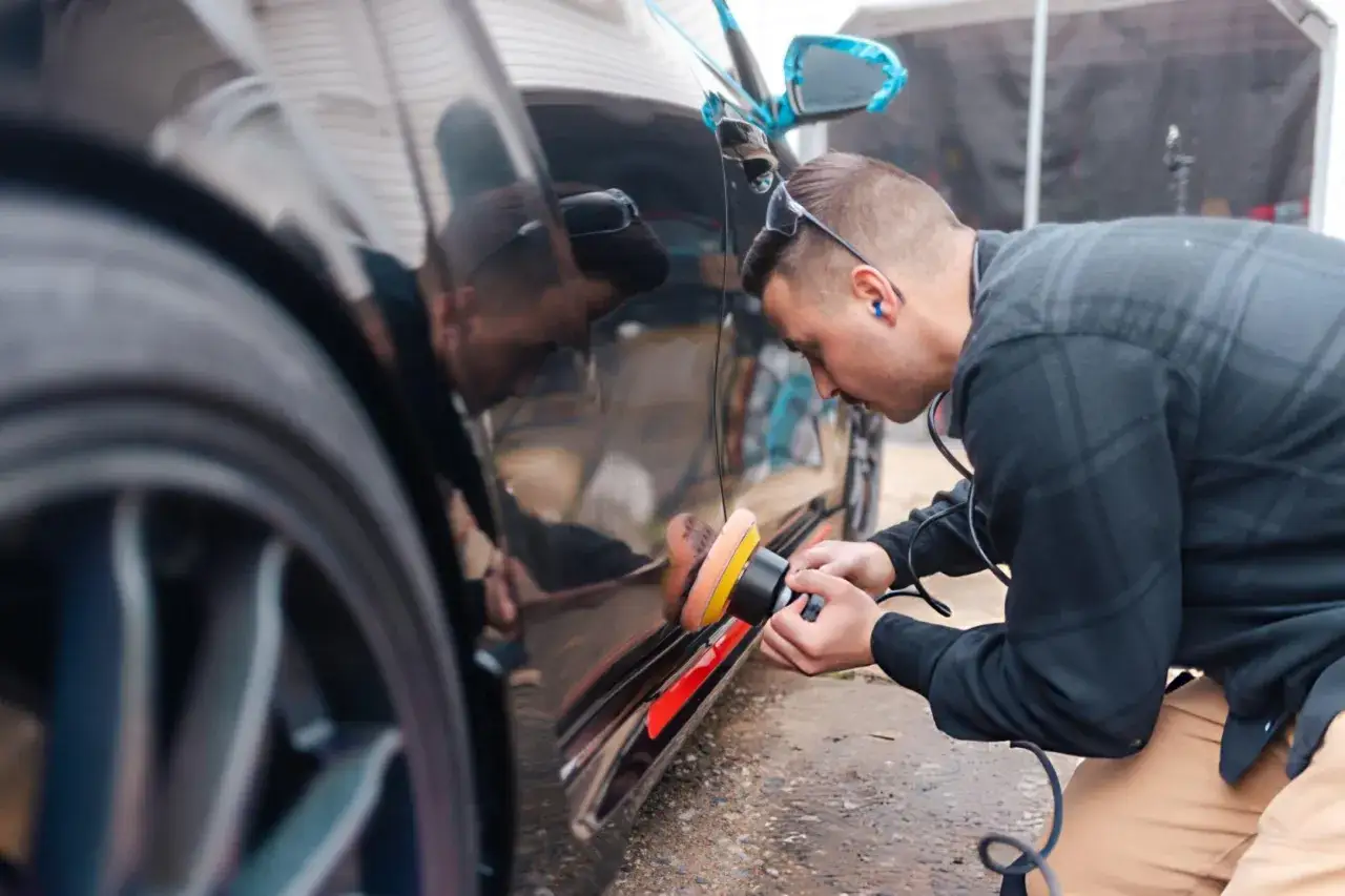 Mann poliert Auto mit exzenter Poliermaschine für perfekten Glanz.