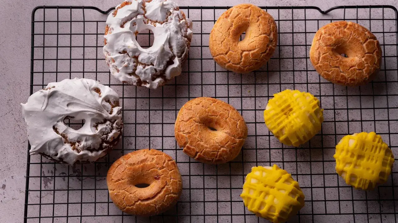 Rosquillas de San Isidro: dos cubiertas de merengue blanco y varias doradas con textura crujiente, junto a otras bañadas en glaseado amarillo.