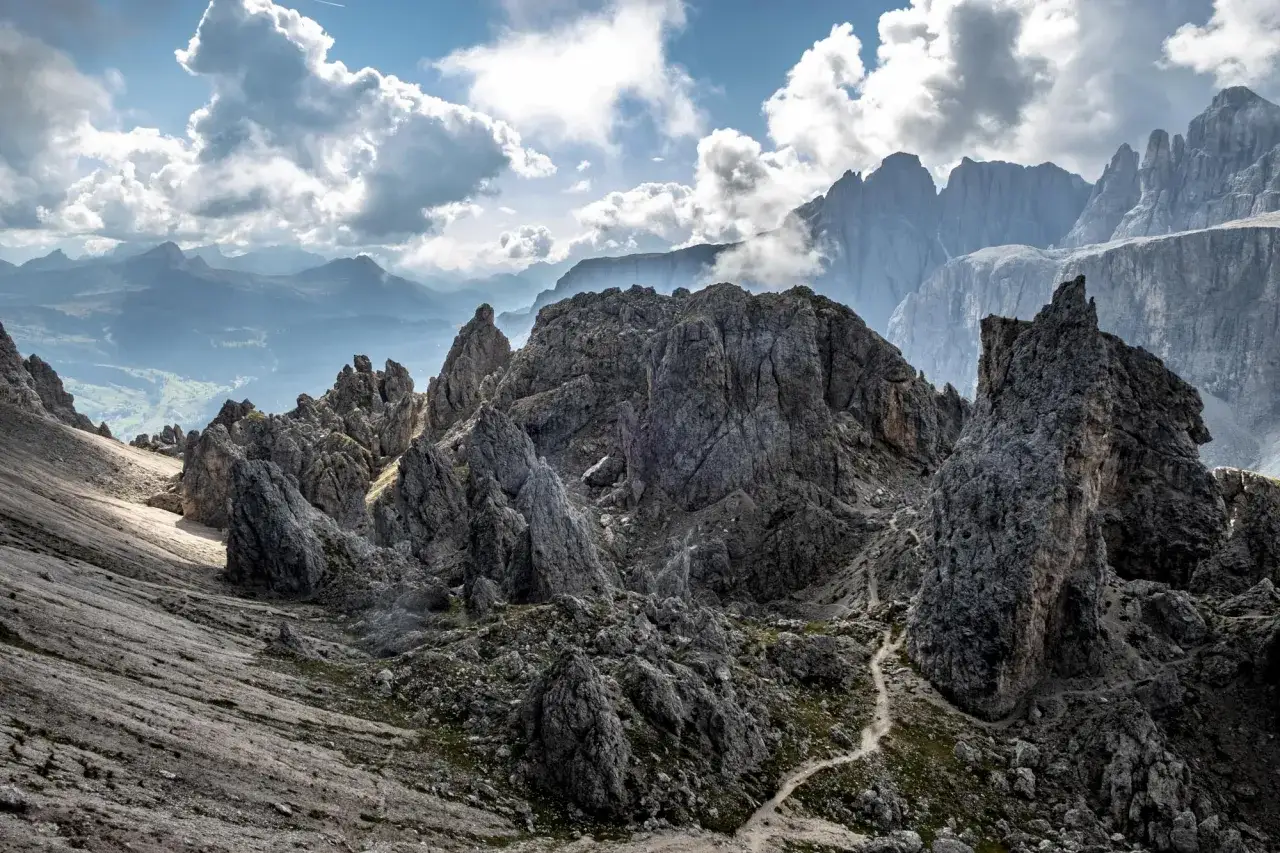 Sentiero tortuoso tra rocce aspre, con vette imponenti che si stagliano all'orizzonte. La **passo gardena altitudine** offre panorami mozzafiato.
