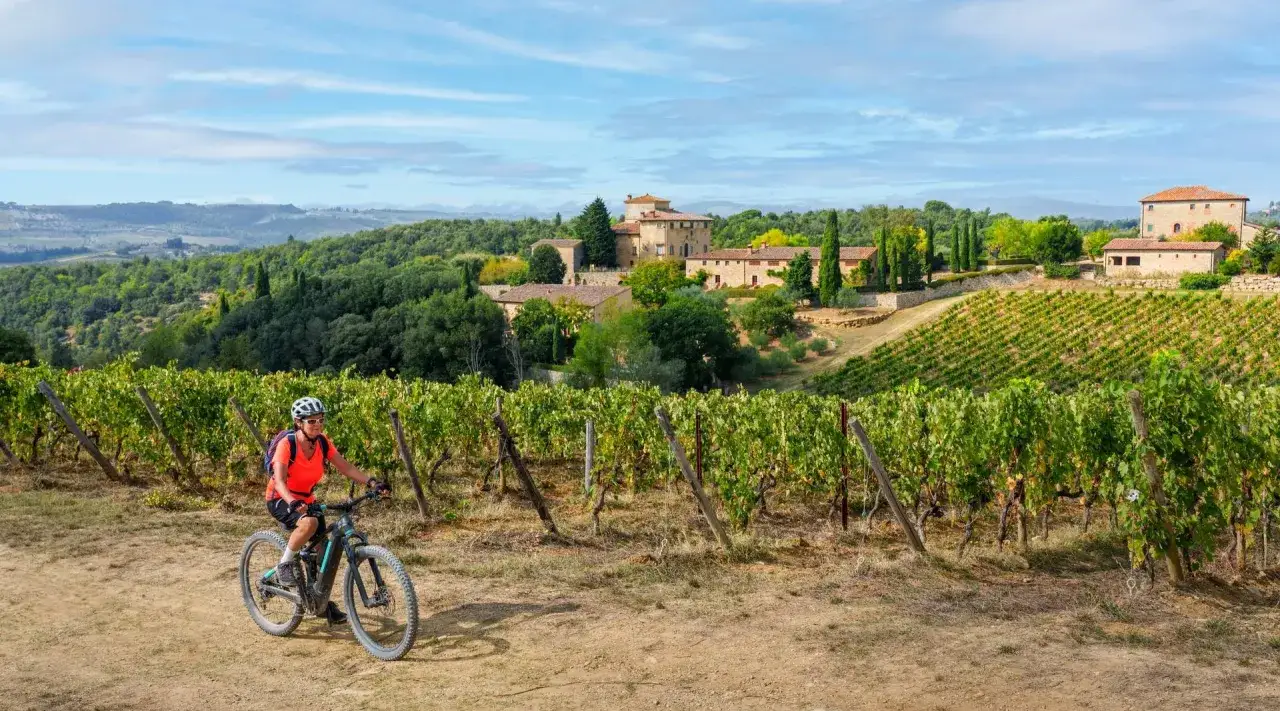 Cyklist njuter av landskapet i Toscana. Här är några **resa till Toscana tips**: utforska vingårdar, njut av maten och upplev den vackra naturen.