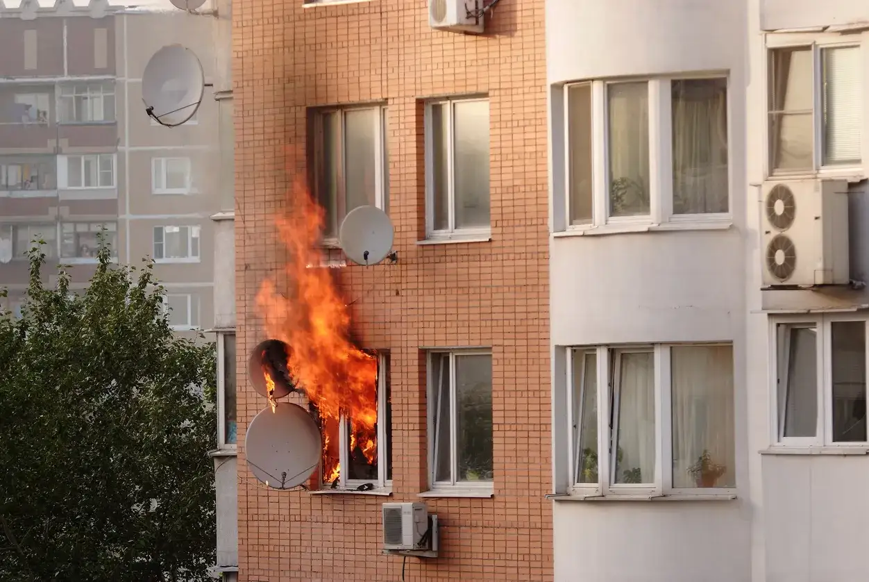 Fiamme alte da una finestra di un palazzo in mattoni, dimostrando quanto il polistirolo sia infiammabile.