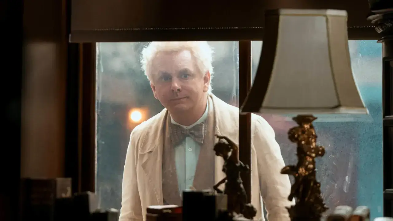 Un ange aux cheveux blonds, prêt pour la saison 3 de Good Omens, regarde par la fenêtre.