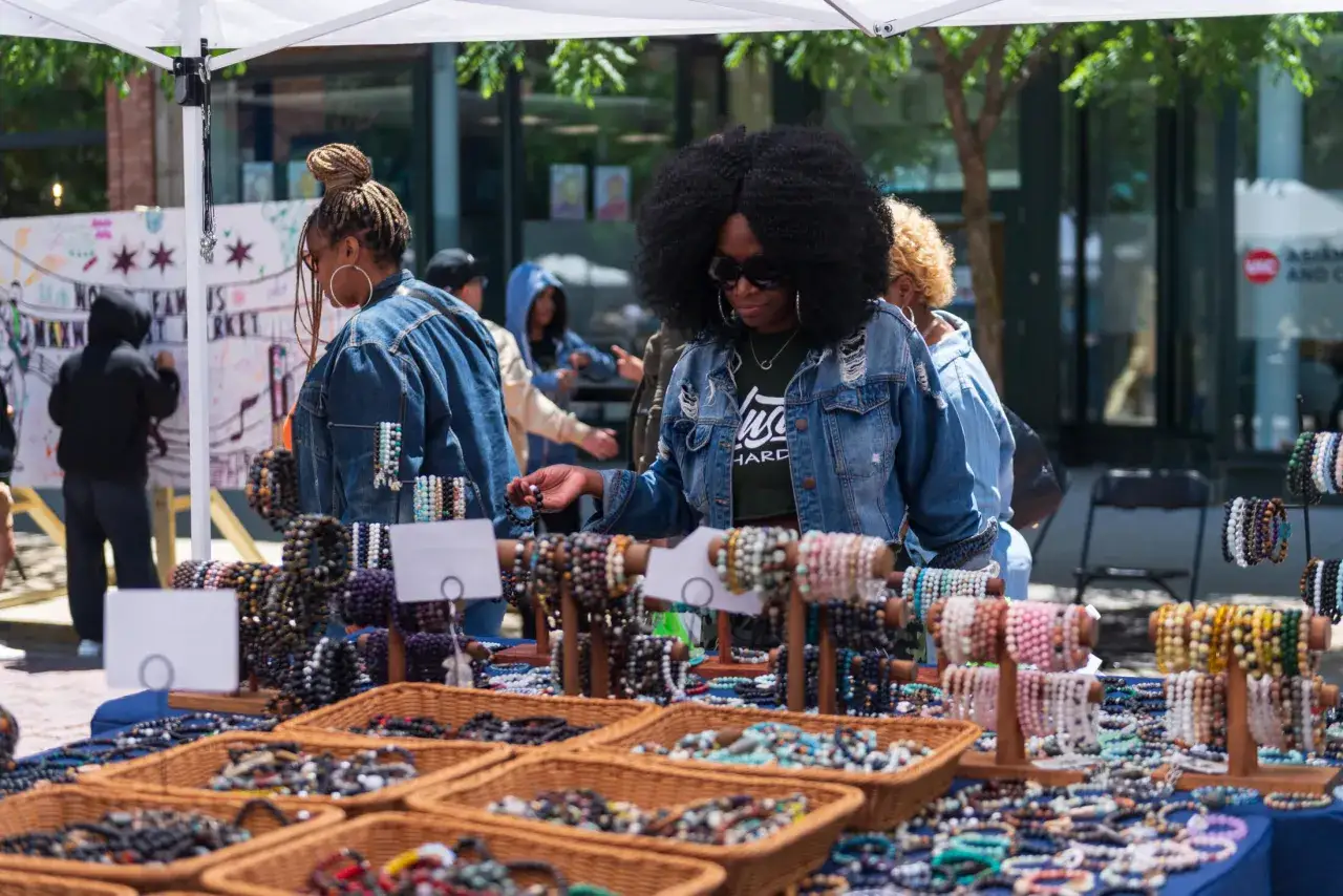 Bunte Perlenarmb&auml;nder auf einem Basar in Kairo. Eine Frau mit Afro-Look w&auml;hlt ein Armband aus.