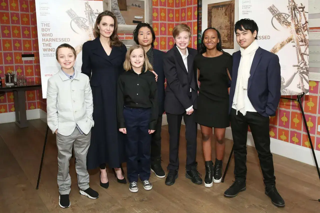 Angelina Jolie z dziećmi pozuje do zdjęcia. Wszyscy uśmiechają się do obiektywu.
