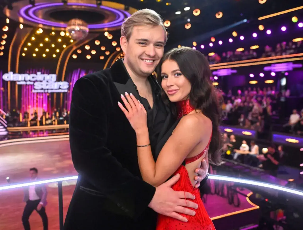 Kevin Mglej i jego partnerka, ubrani w eleganckie stroje, pozują na scenie