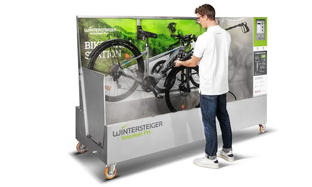 Mężczyzna myje rower w profesjonalnej myjni rowerowej. Urządzenie Wintersteiger Veloclean Pro zapewnia szybkie i skuteczne czyszczenie.