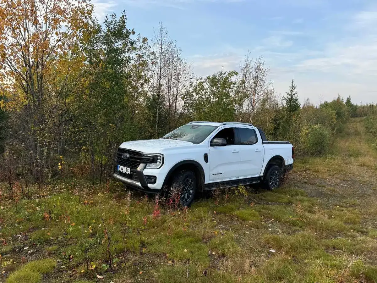 Vit Ford Ranger Wildtrak st&aring;r parkerad vid en skogsv&auml;g. Ett litet problem med terr&auml;ngen, men bilen klarar det.