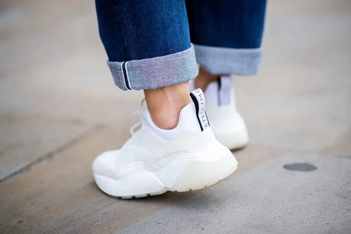 Scarpe bianche di pelle con jeans risvoltati. Scopri come lavare le scarpe bianche di pelle in lavatrice per mantenerle perfette.