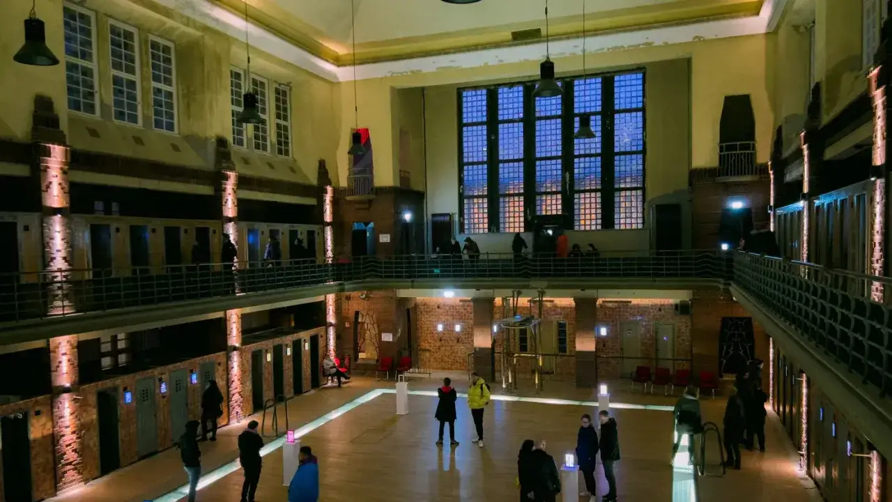 Das stadtbad reloaded: Menschen erkunden die umgestaltete Halle mit ihren vielen Kabinen und Galerien, beleuchtet von warmem Licht.