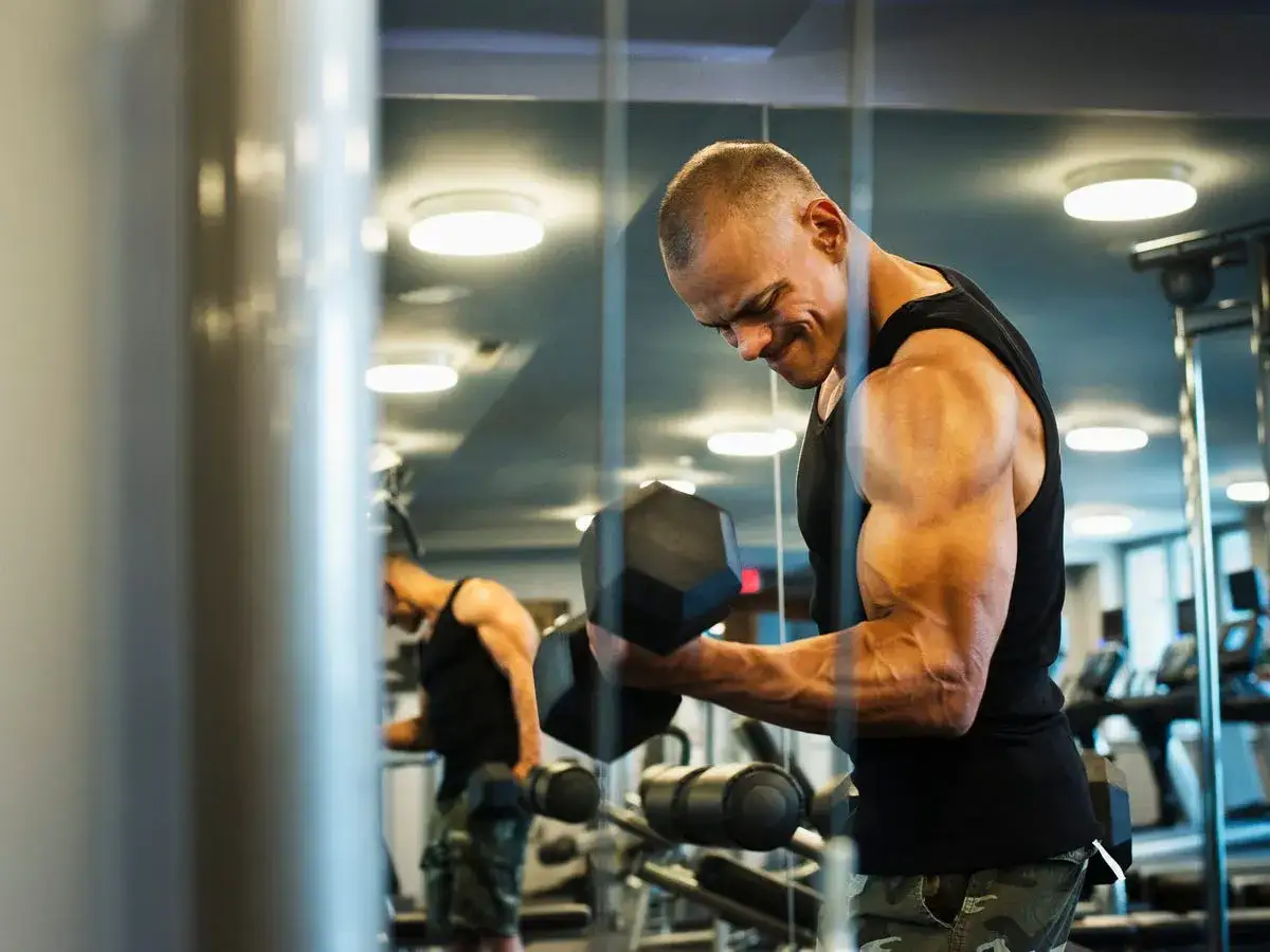 Mężczyzna ćwiczy biceps z hantlami, pokazując najlepsze ćwiczenia na biceps.