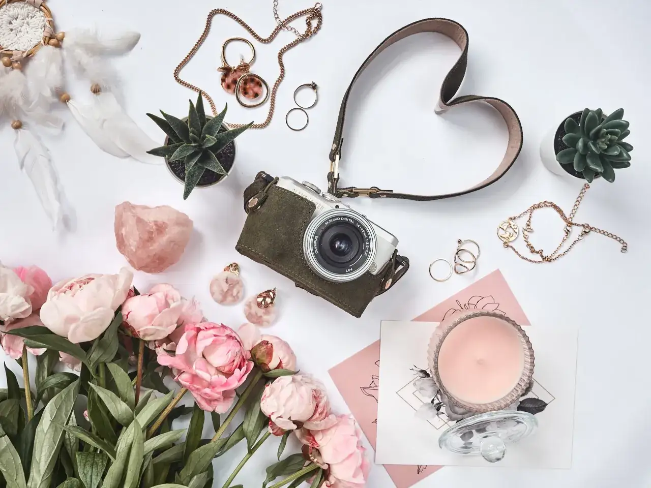 Zdjęcia flat lay: aparat, piwonie, łapacz snów, biżuteria, świeca i sukulenty.