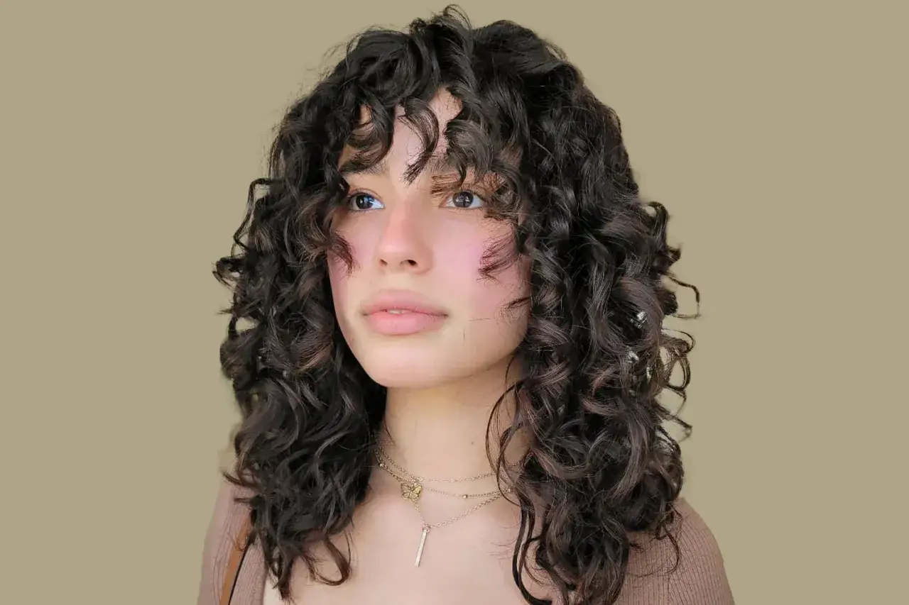 Chica con pelo rizado con flequillo, luciendo un estilo moderno y natural.