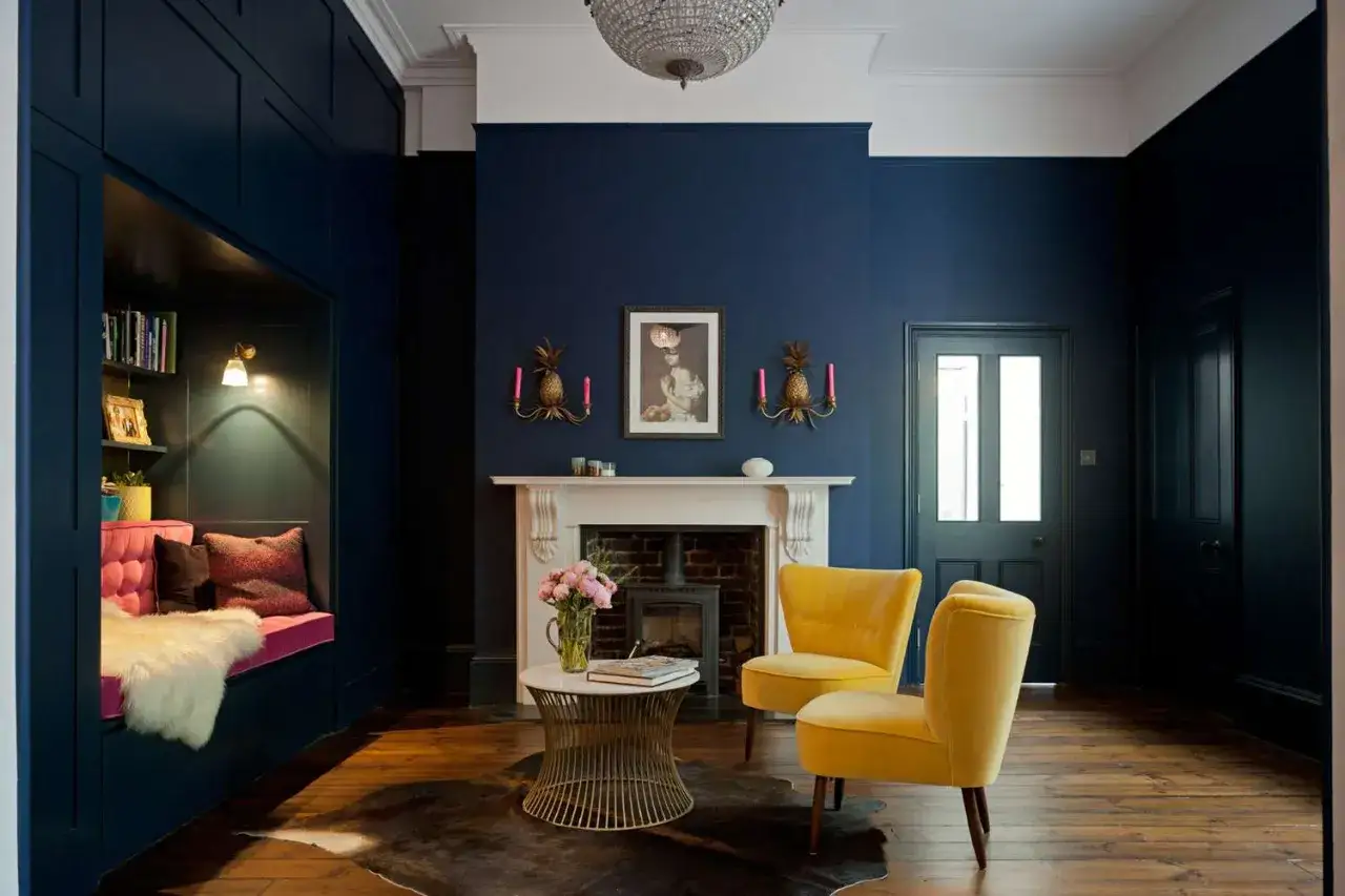 Ein Wohnzimmer in tiefem Blau mit gelben Akzenten. Die Frage, welche Farbe passt zu Blau, wird hier mit leuchtendem Gelb beantwortet.
