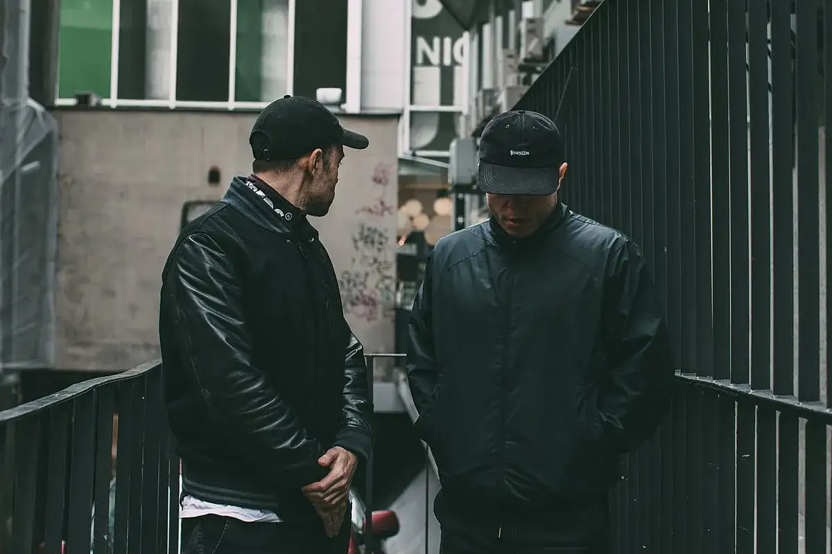 Dwóch raperów w czapkach, jeden w skórzanej kurtce, drugi w bomberce. Ich styl to pro8l3m cytaty rap.
