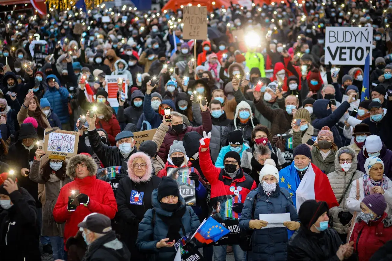 Tłum ludzi z telefonami i latarkami na proteście. Transparenty