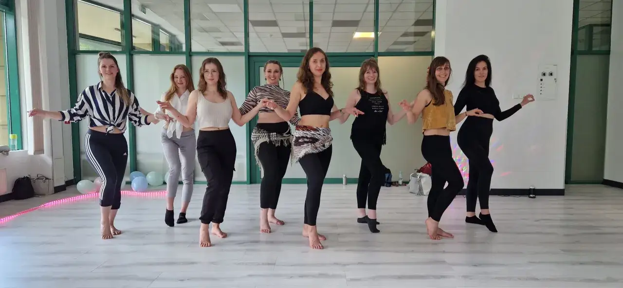 Grupa kobiet tańczy w rytm piosenek na wieczór panieński. Wesoła atmosfera i radosne ruchy.