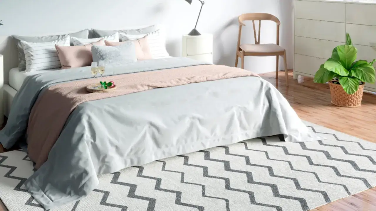 Alfombra con diseño de zigzag gris y blanco complementa la cama y otros tipos de alfombras en un dormitorio moderno.