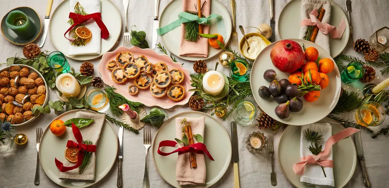 Festlich gedeckter Tisch für ein gesundes Weihnachtsessen: Nüsse, Früchte, Plätzchen und Kerzen sorgen für Weihnachtsstimmung.