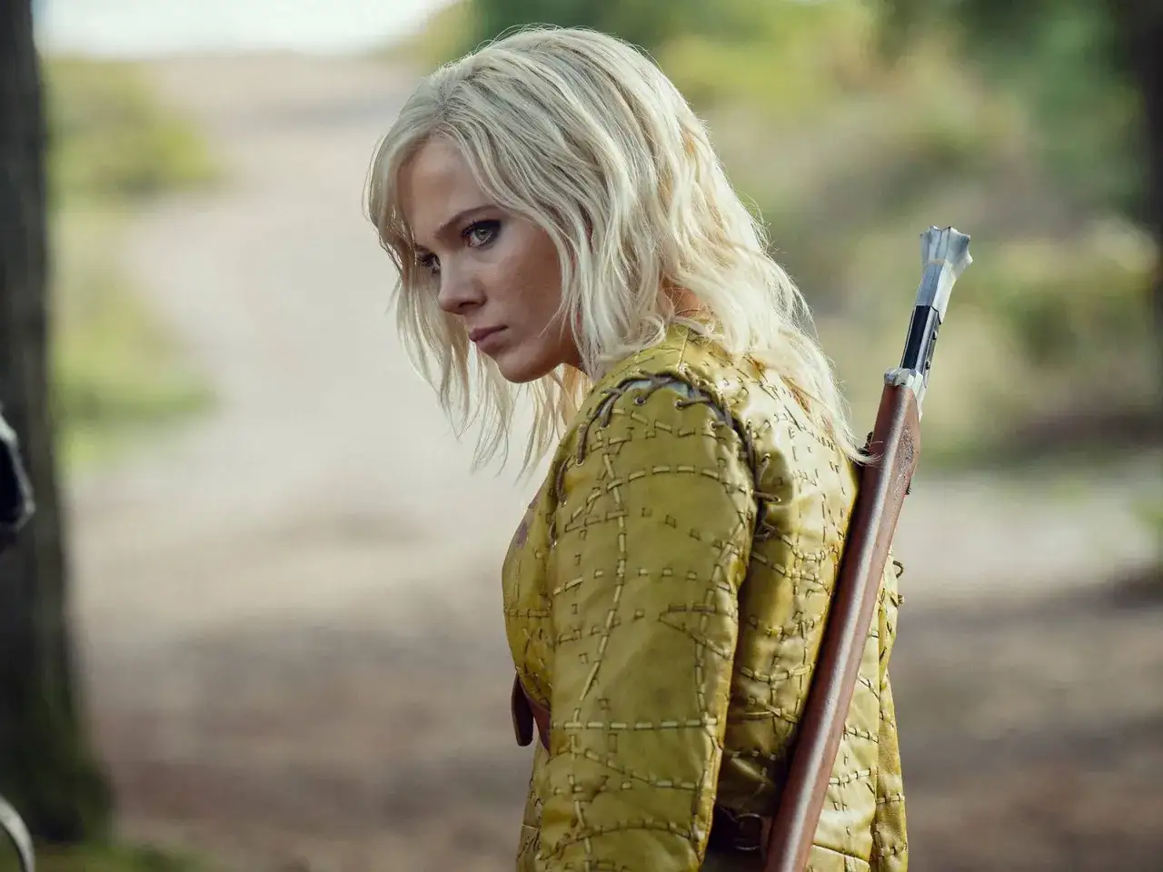 Ciri, con su ic&oacute;nico cabello rubio y mirada intensa, se prepara para la acci&oacute;n en la **the witcher temporada 5**. Lleva una armadura amarilla y una ballesta a la espalda.