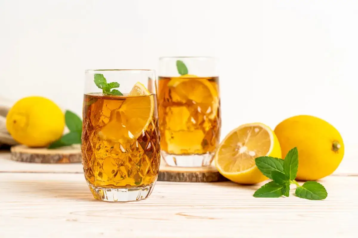 Orzeźwiający ice tea z plasterkami cytryny i listkami mięty, podany w szklankach z lodem.